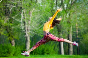 Young beautiful girl doing gymnastic jumps outdoors