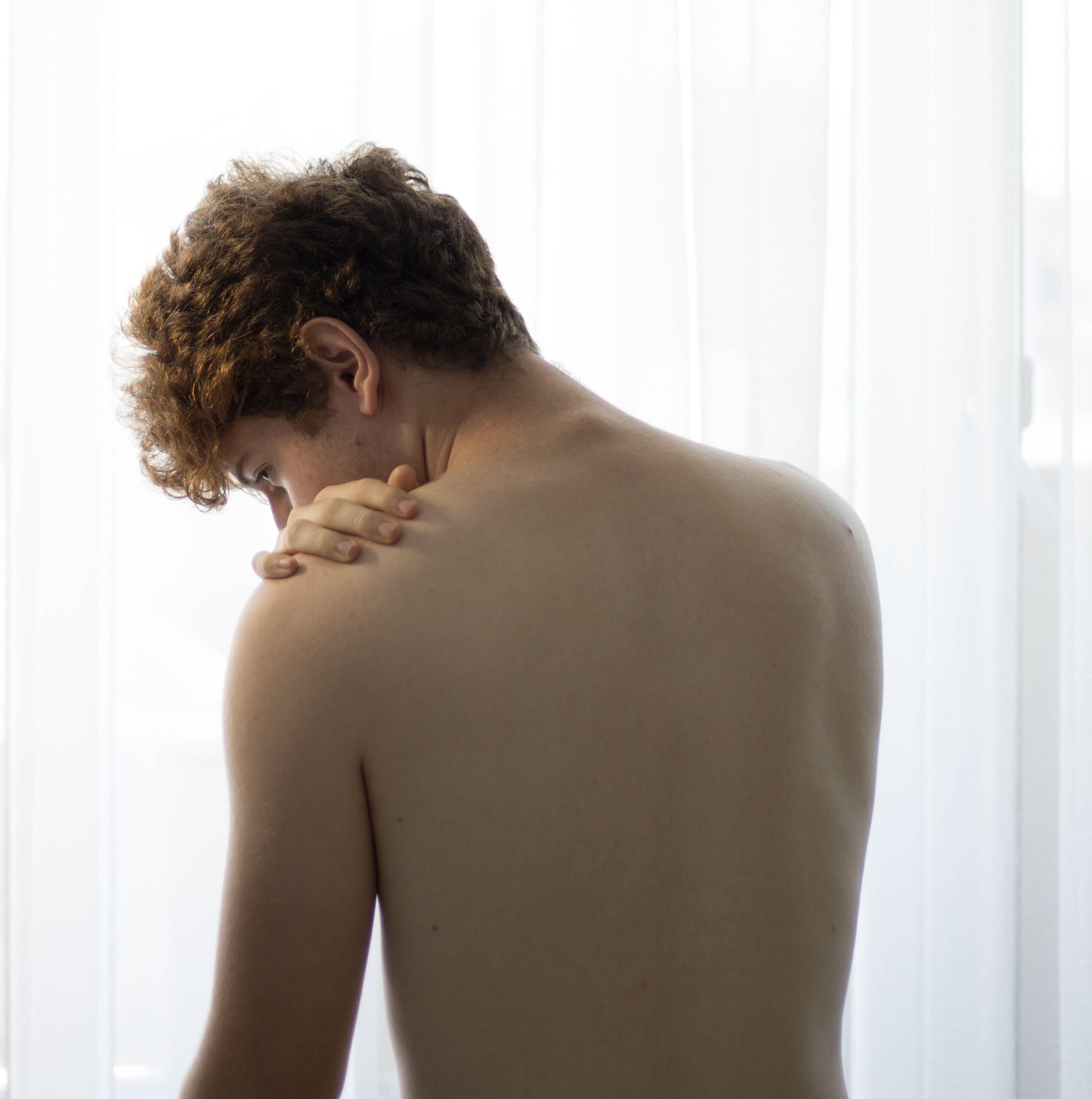 Young boy with pain from stiff shoulder and neck