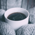 Person wearing gloves and drinking hot tea protecting their immunity in the winter