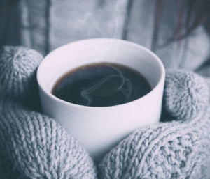 Person wearing gloves and drinking hot tea protecting their immunity in the winter
