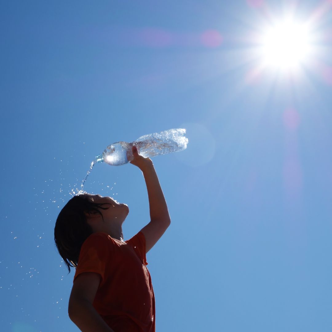 A person pouring water over themselves in hot weather to relieve the signs of heat their experiencing
